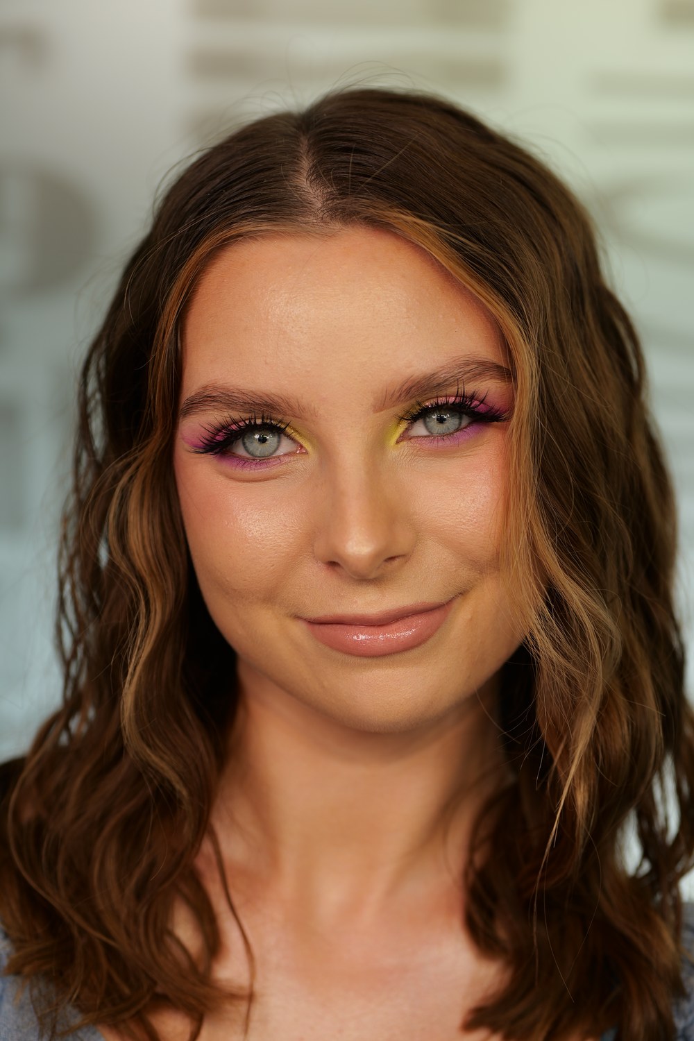 Modelka z różowo-żółtym makijażem festiwalowym i fioletową kreską